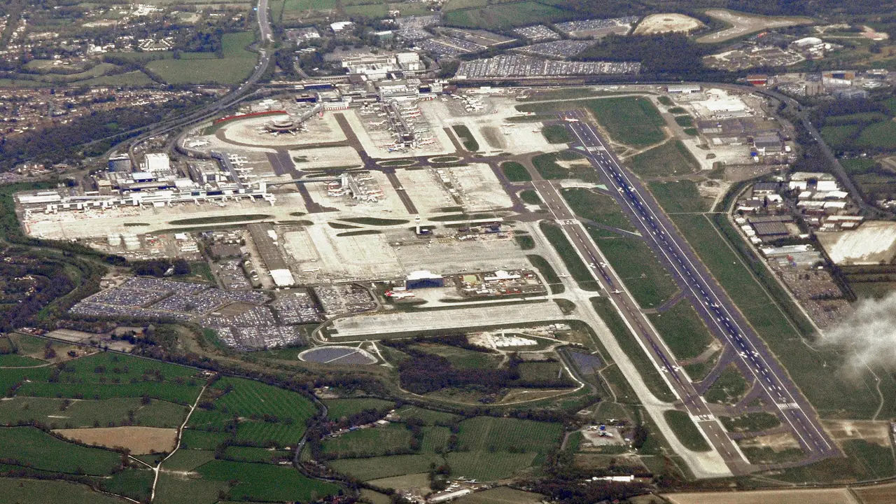Aerial view of Gatwick Airport's runway, terminals, aprons and surrounding land.